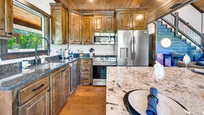 A modern kitchen with wooden cabinets, stainless steel appliances, and a marble countertop. - Stargazing Dome, Hot Tub, Fire Pit, Luxury Cabin near Broken Bow (Broken Bow)