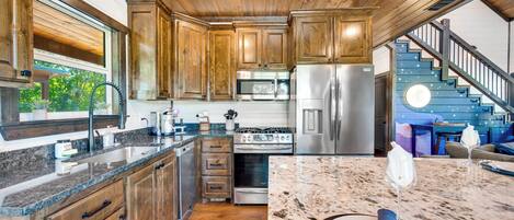 A modern kitchen with wooden cabinets, stainless steel appliances, and a marble countertop.
