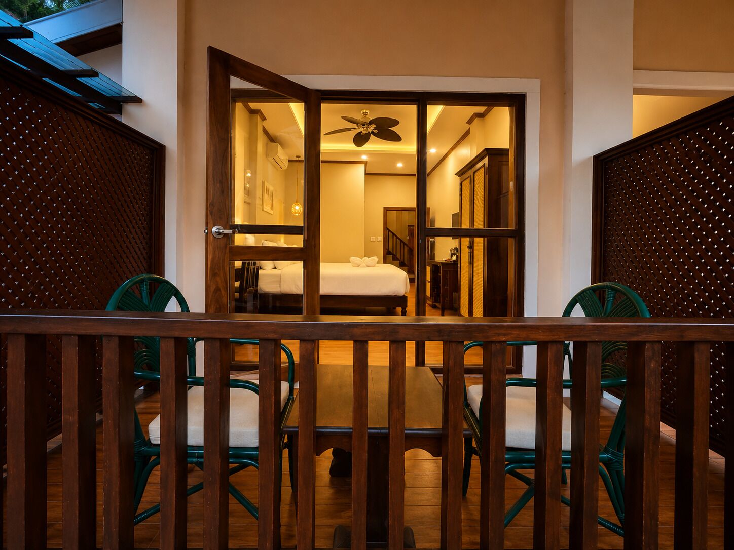 Una habitación con una cama, un ventilador de techo y vistas por una puerta de madera.