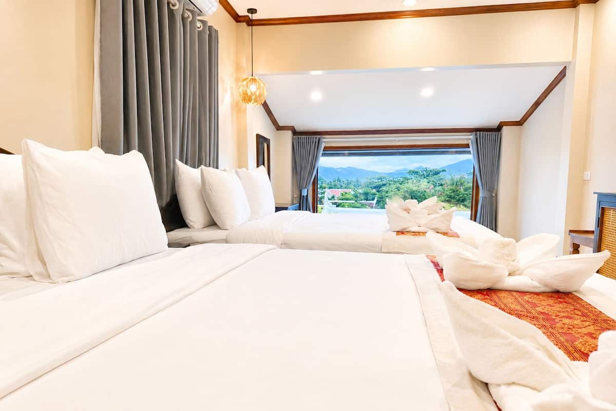 Een hotelkamer met twee bedden, uitzicht op de omgeving en een kroonluchter.