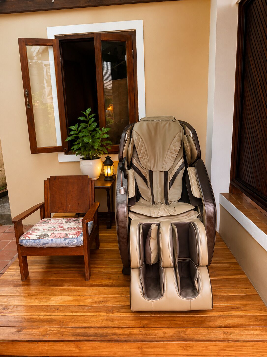 Un fauteuil massant, une chaise en bois avec un coussin à motifs floraux et une plante en pot sur une terrasse en bois.