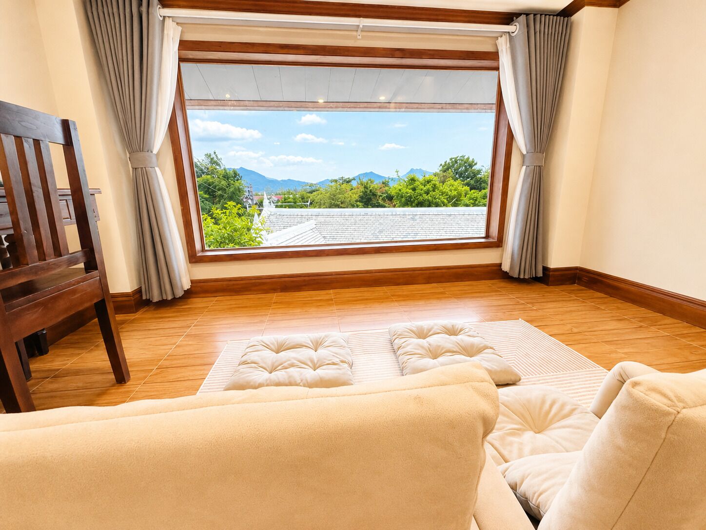 Una habitación con un ventanal grande, suelo de madera y un sofá con vistas a las montañas.