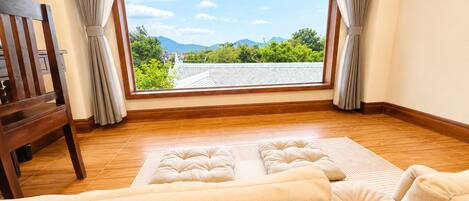 Una habitación con un ventanal grande, suelo de madera y un sofá con vistas a las montañas.