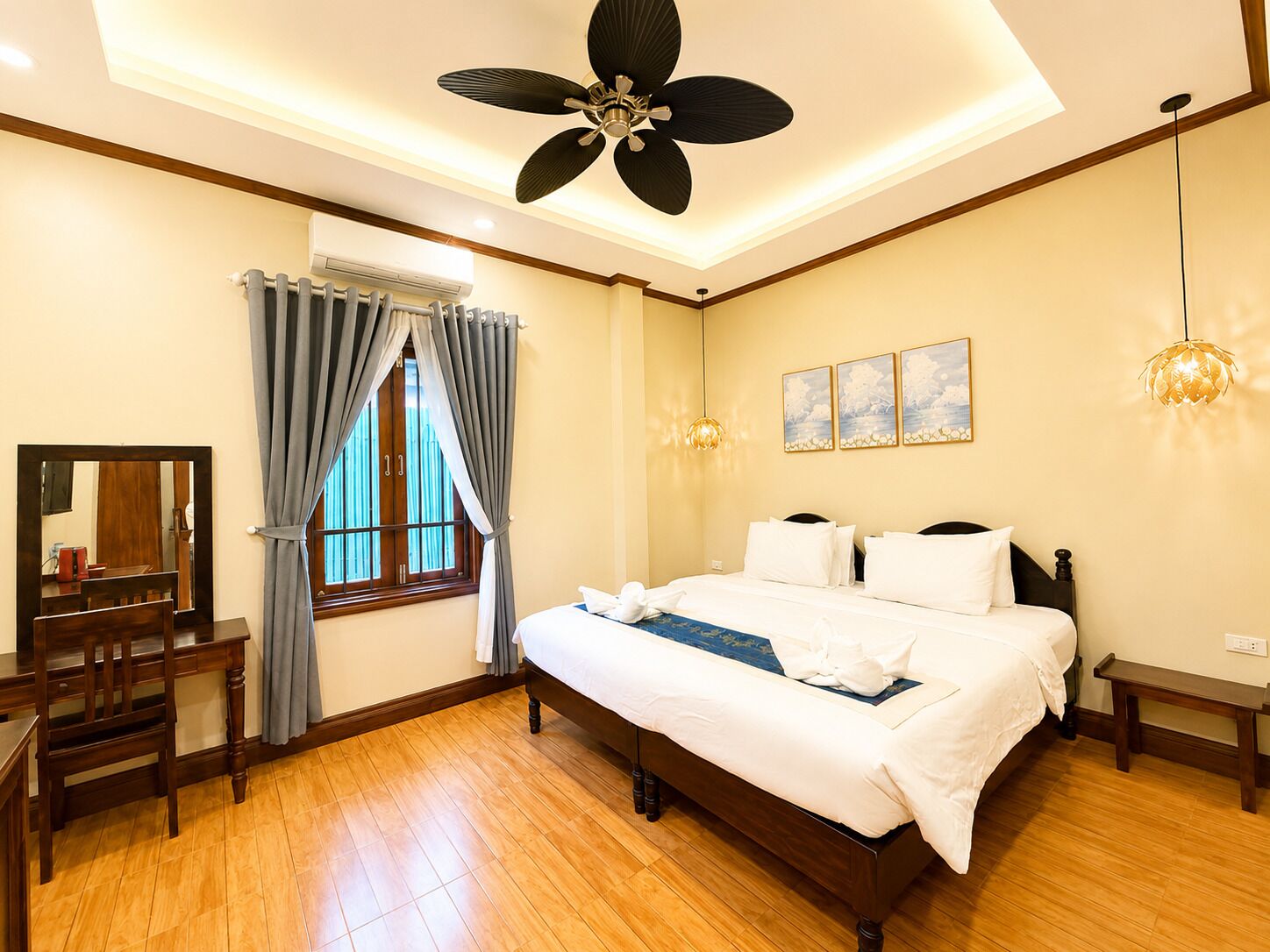 A bedroom with a bed, a desk, a chair, a ceiling fan, and a window with curtains.