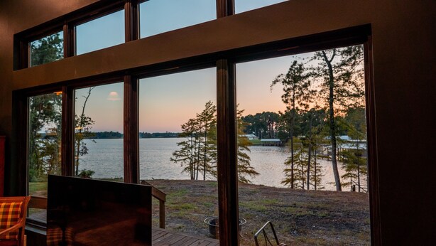 A room with large windows overlooking a body of water and trees. - Newly Renovated, Cozy Mid-Lake Cabin; Sleeps 10 (Many)