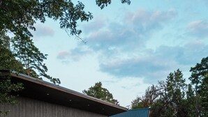 A modern building with a deck, outdoor seating, and a large window. - Newly Renovated, Cozy Mid-Lake Cabin; Sleeps 10 (Many)