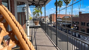 A balcony with a view of palm trees and buildings.