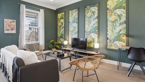 A living room with a sofa, chairs, a TV, and artwork on the walls.