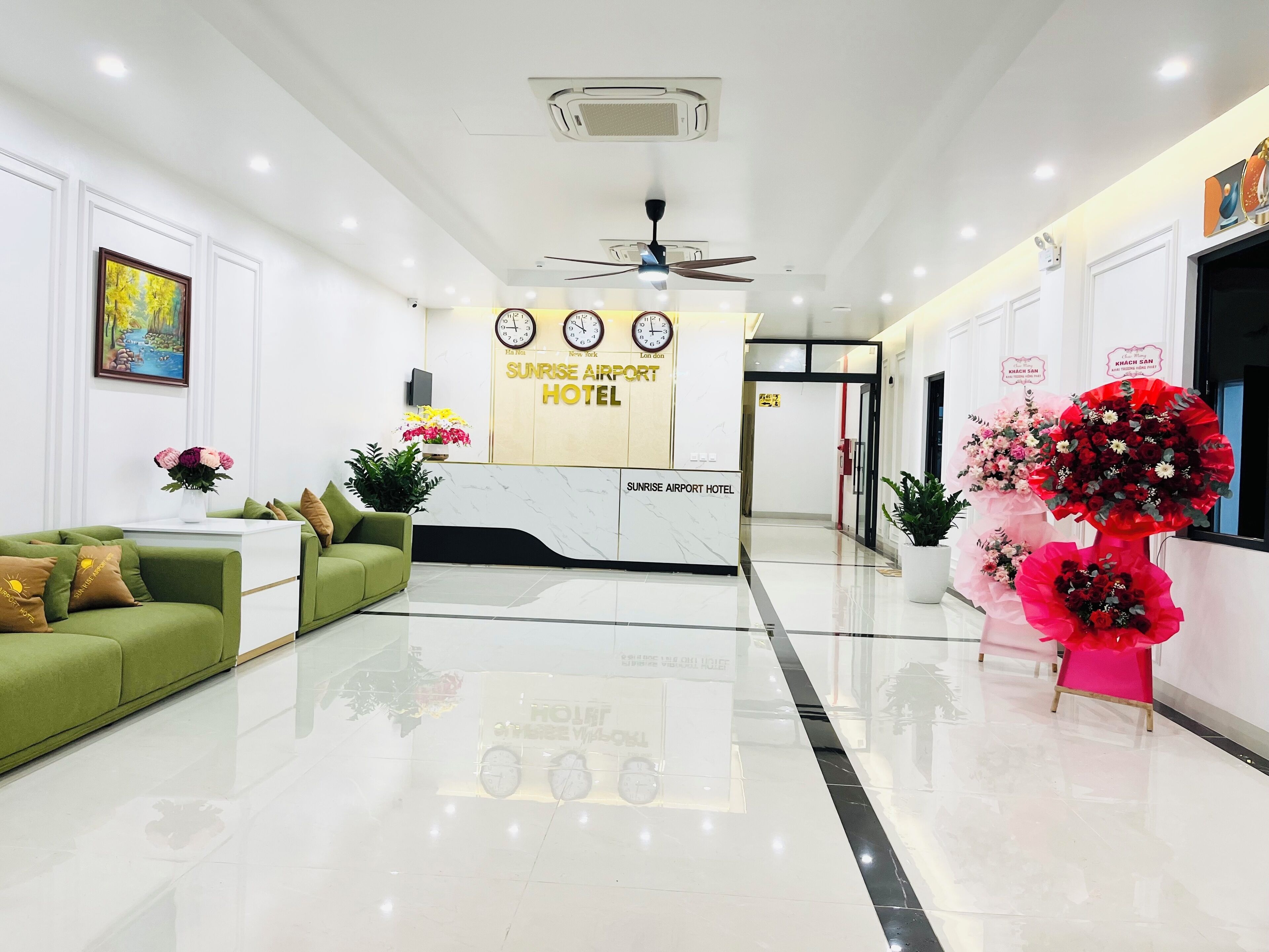 A hotel reception area with a reception desk, a green sofa, and a clock.
