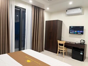 Een hotelkamer met een bed, een bureau, een stoel, een kledingkast, een televisie en een airconditioner.