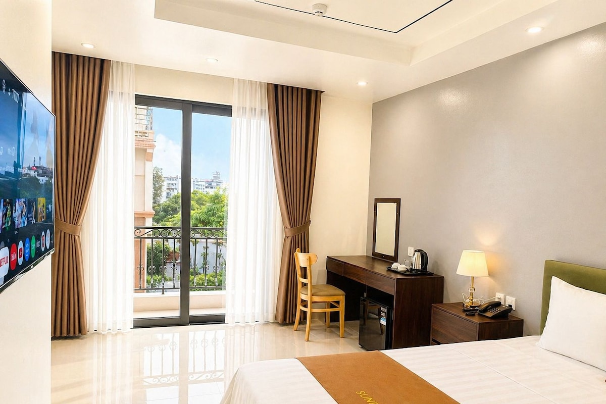 Une chambre d’hôtel équipée d’un lit, d’un bureau, d’une chaise, d’une télévision et offrant une vue sur l’extérieur.