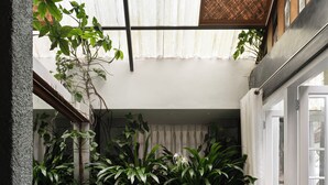 A small, enclosed bathroom with a wooden floor, a black bathtub, and various plants. - SpiceTree Rajakumari (Udumbanchola)