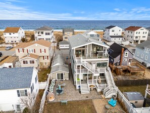 A coastal residential area with multiple houses, a large two-story building with a balcony, and a view of the ocean. - Bedroom Ocean Views | Steps to Beach | New Kitchen (Salisbury)