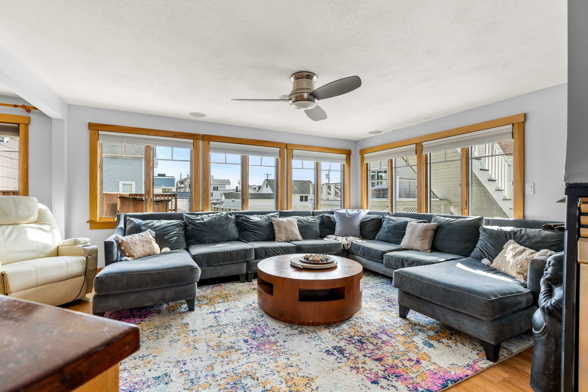 A modern living room with a sectional sofa, a round coffee table, and large windows offering city views.