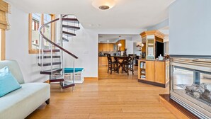 A modern living room with a spiral staircase, a dining area, and a kitchen in the background.