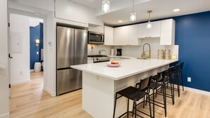 Uma cozinha moderna com eletrodomésticos de aço inoxidável, uma ilha branca com banquetas e paredes azuis.