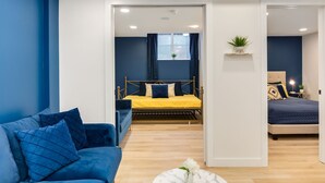 Quarto moderno com uma cama, um sofá azul e uma pequena mesa com uma planta.