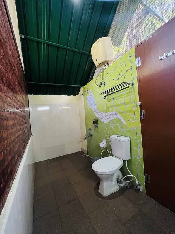 A small bathroom with a toilet, a shower, and a green ceiling.