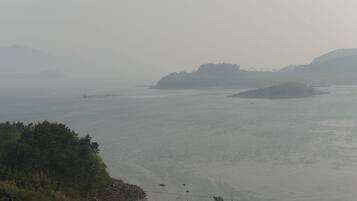 Paisaje costero con agua tranquila, un faro y islas a la distancia.