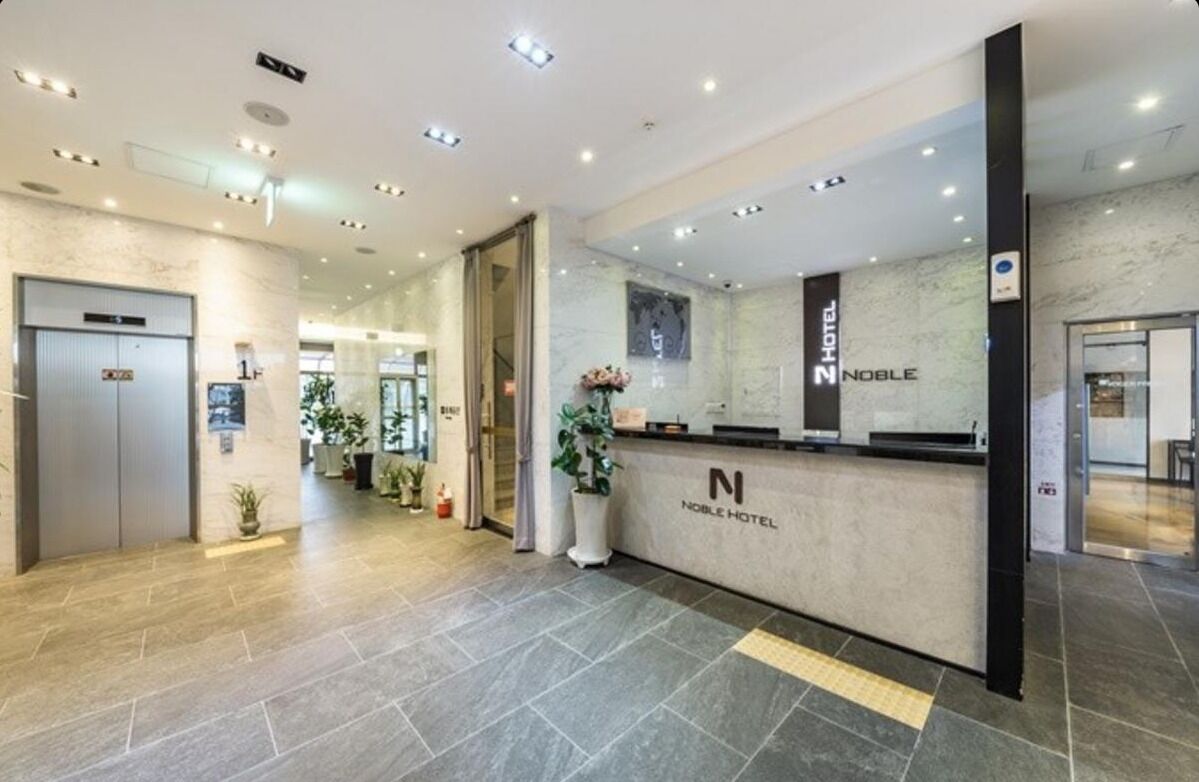 Un'area di ricevimento di un hotel con una scrivania in marmo, un display digitale e vista libera sulla hall.