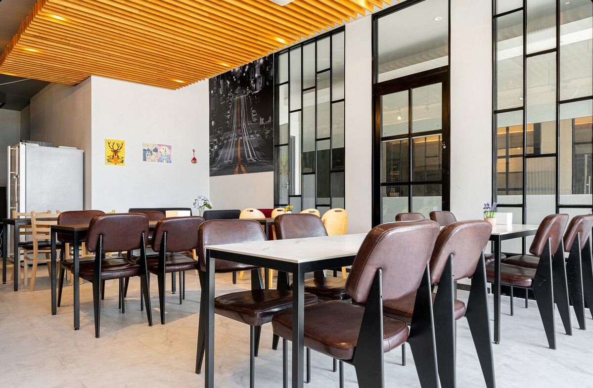 A modern dining area with wooden ceiling panels, large windows, and a whiteboard on the wall.