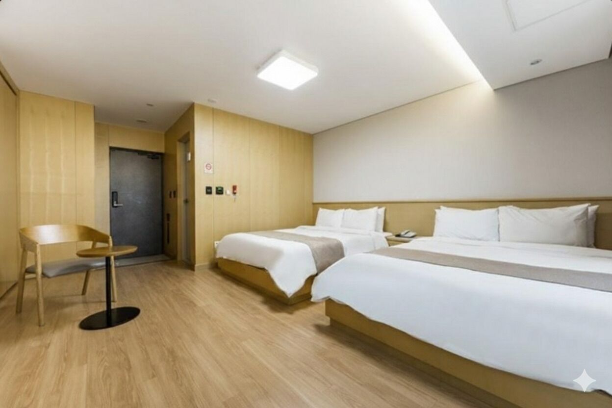 Une chambre d’hôtel avec deux lits, une petite table et une porte donnant sur une autre pièce.