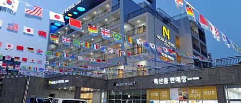 A multi-story hotel with balconies, a mobile press office, and various flags.