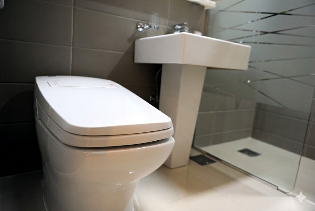 Un baño moderno con inodoro, lavamanos y cabina de ducha de vidrio.