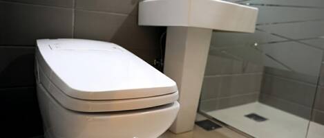Un baño moderno con inodoro, lavamanos y cabina de ducha de vidrio.