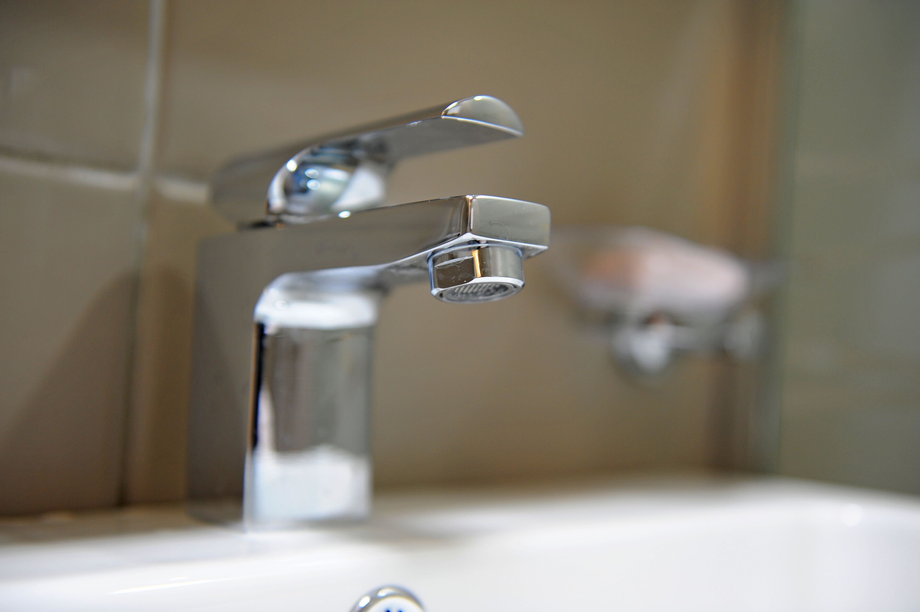 A bathroom sink with a chrome faucet and a mirror.
