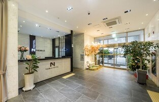 Zona de recepción de un hotel con mostrador de mármol, una planta en maceta y un árbol de Navidad.