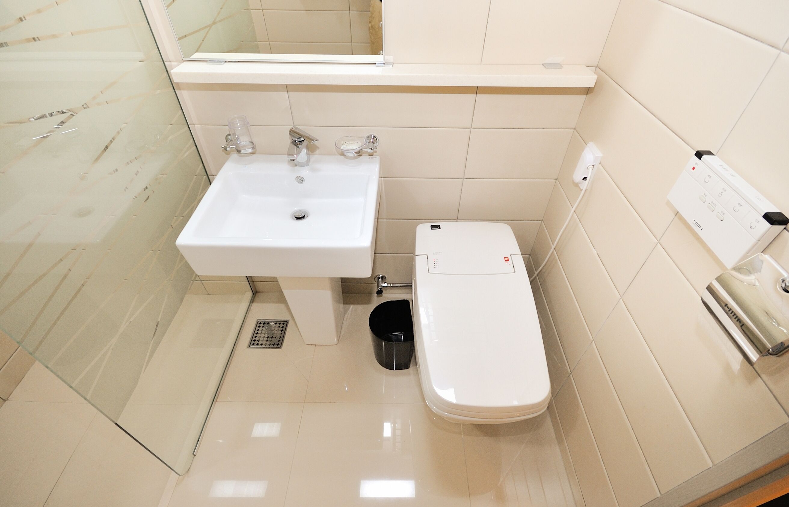 A bathroom with a white sink, toilet, and a mirror above the sink.