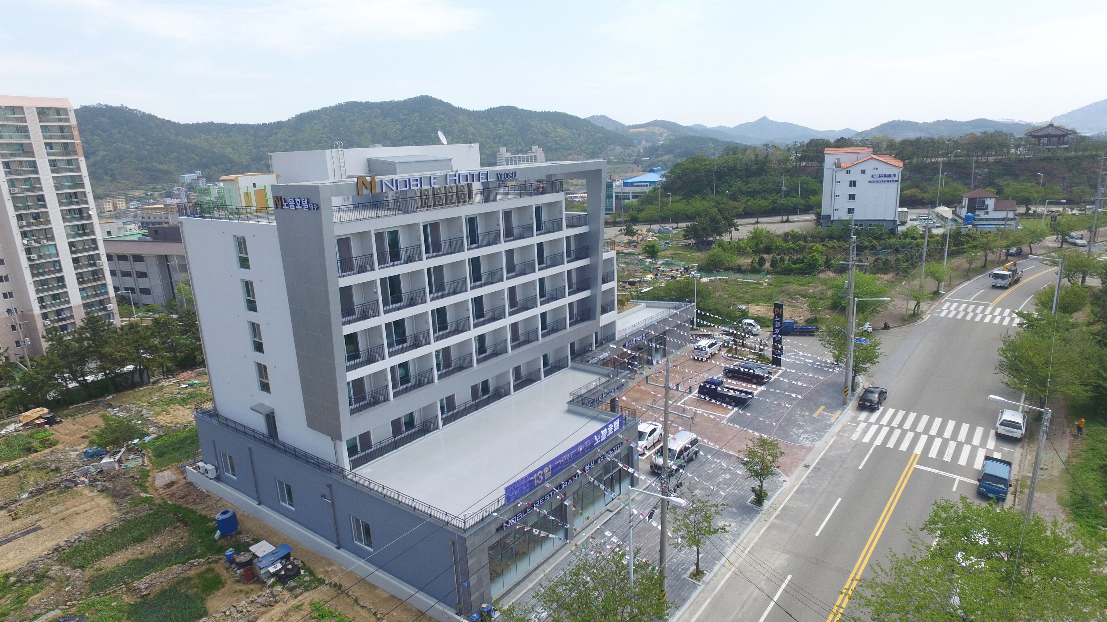 A multi-story hotel with a modern design, featuring balconies on the upper floors and a ground-level restaurant.