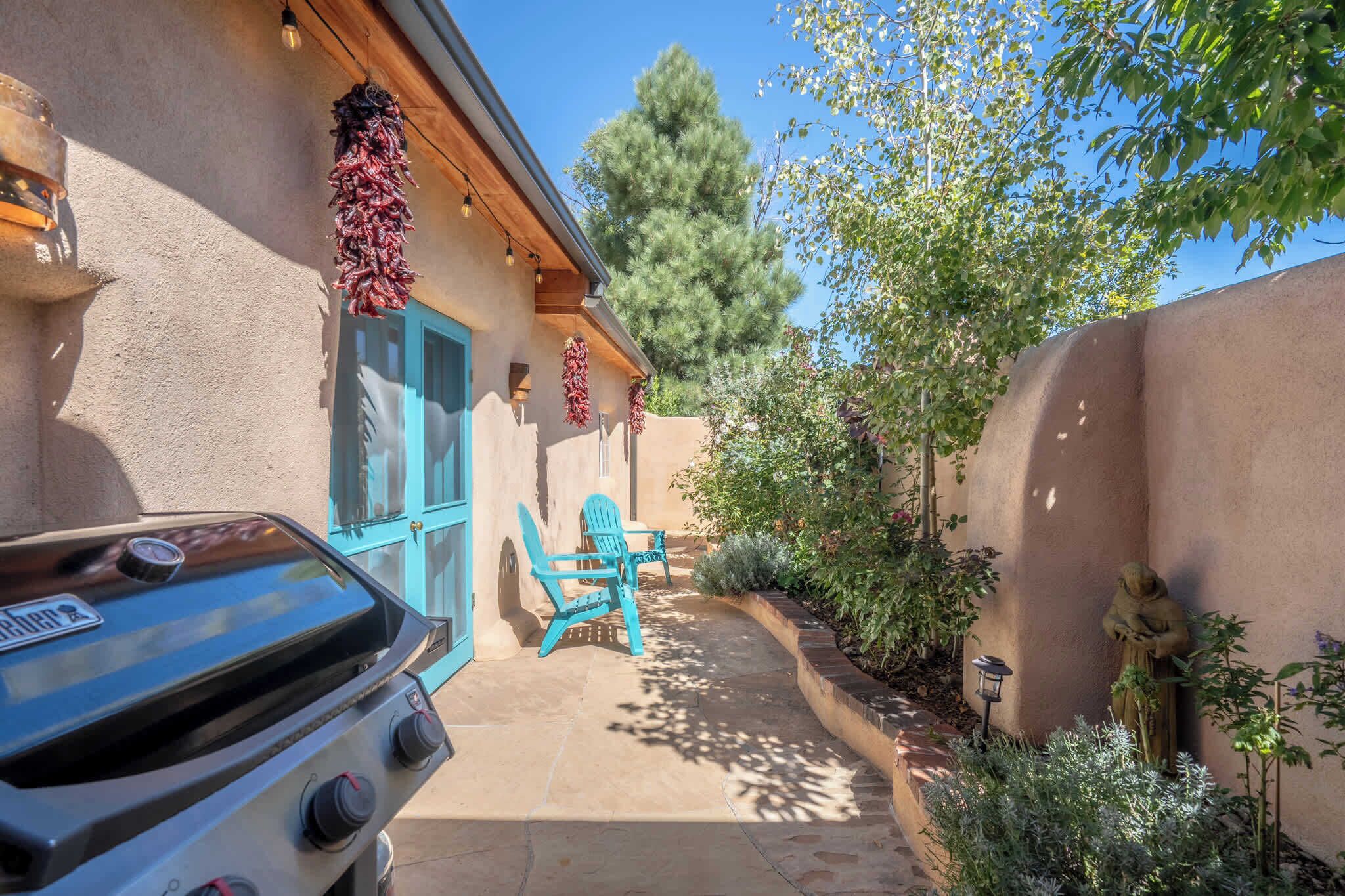 A patio area with a barbecue grill, outdoor chairs, and a statue.