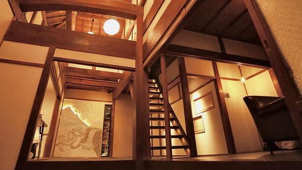 A multi-level wooden interior with a staircase, wooden beams, and hanging spherical lights. - Rent a whole house, sauna, and garden (Kaizuka-shi)
