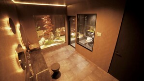 A modern bathroom with a large mirror, a sink, and a toilet. There is a small plant and a decorative item on the counter. - Rent a whole house, sauna, and garden (Kaizuka-shi)
