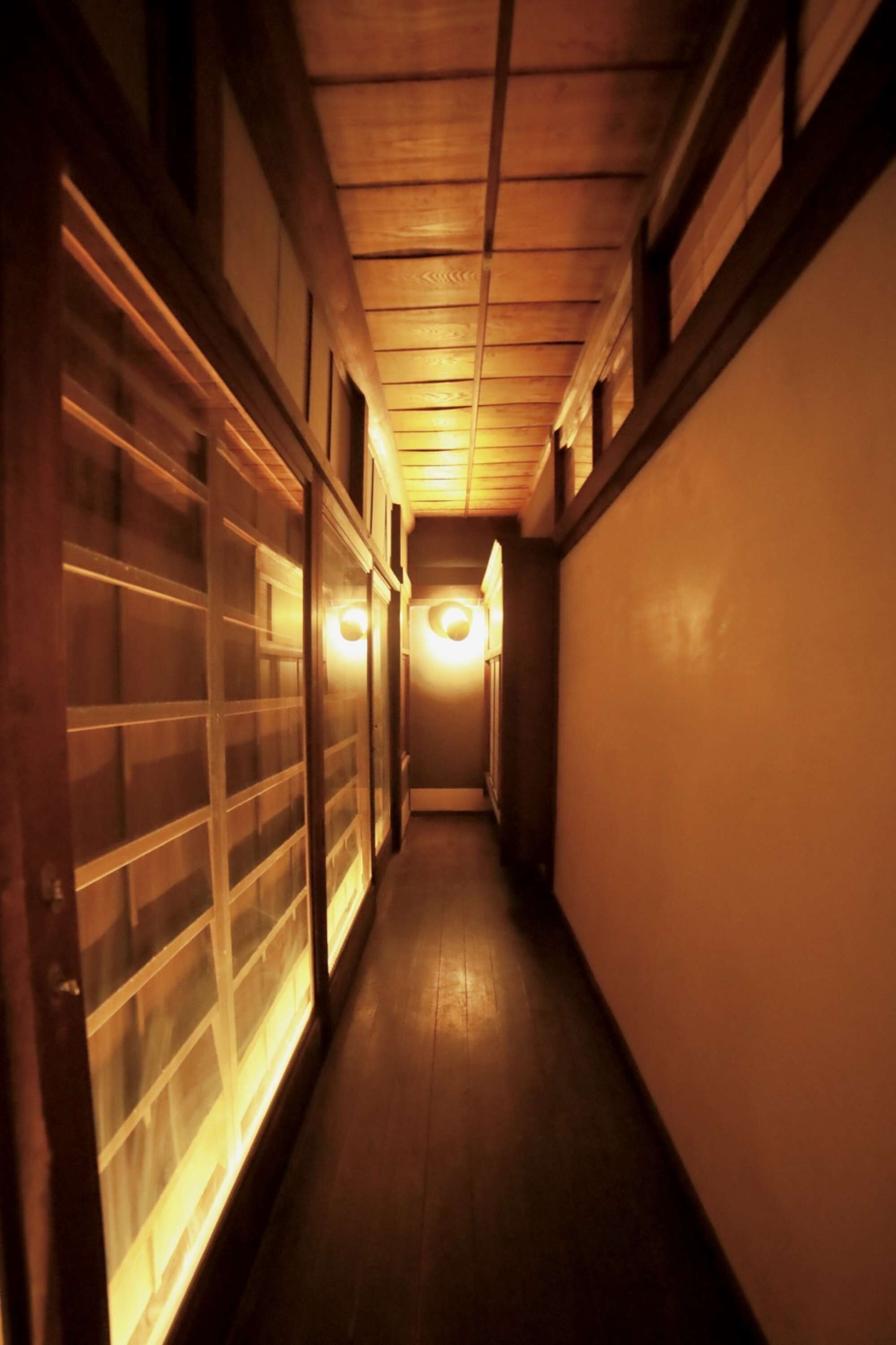 Un couloir étroit, doté d’un plancher en bois et éclairé par une source de lumière chaleureuse au fond.