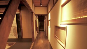 A hallway with wooden flooring, a staircase on the left, and framed pictures on the walls. - Rent a whole house, sauna, and garden (Kaizuka-shi)