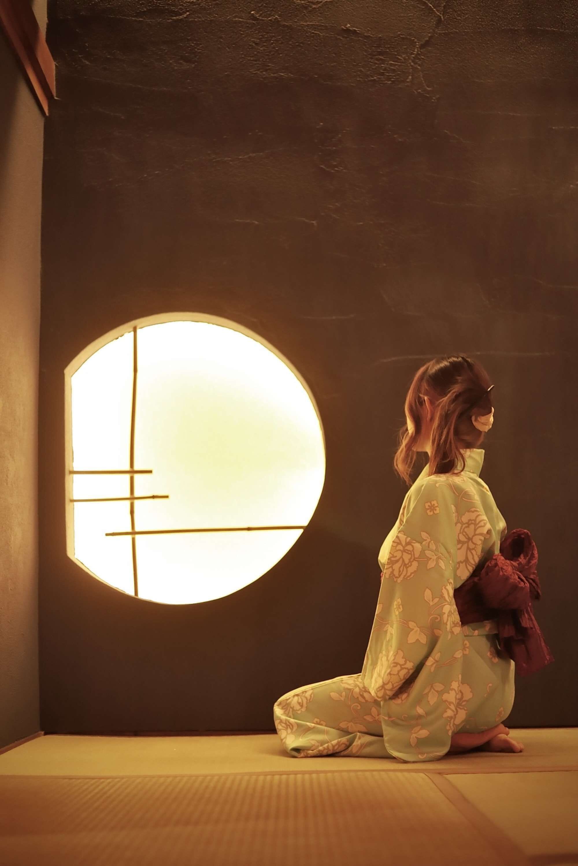 A traditional Japanese room with tatami flooring, a shoji screen, and a person in a kimono.
