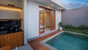 Une cuisine moderne dotée d’une cuisinière intégrée et d’une machine à café, une petite piscine avec une terrasse en bois, et une porte-fenêtre coulissante donnant sur une chambre.
