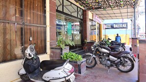 A hotel entrance with a covered porch, a parked scooter, and a motorcycle. - Hotel Dhayalan (Mayiladuthurai)
