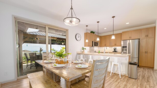 A modern kitchen with wooden cabinets, stainless steel appliances, and a dining area with a wooden table and chairs. - Hawaiian Pakele-Ocean View Estate (Waianae)