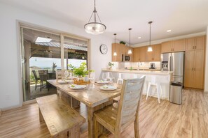 Una cucina moderna con mobili in legno, elettrodomestici in acciaio inossidabile e un'area pranzo con tavolo e sedie in legno.