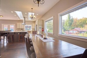 A spacious kitchen with a long counter, pendant lighting, and a large window offering a view of the outdoors. - Riverfront with Hot Tub | 4 King Beds, 4 Mi to Leavenworth (Peshastin)
