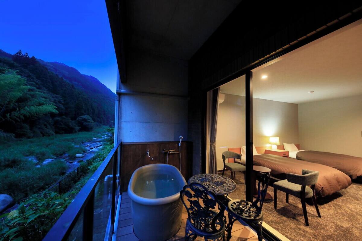 A balcony with a hot tub, a bed, and a table with chairs.