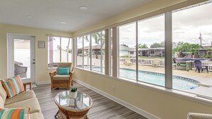 A spacious room with a large window overlooking a pool and outdoor area, furnished with wicker chairs and a glass coffee table. - Canal-Front Retreat w/ Boat Dock on Merritt Island (Merritt Island)