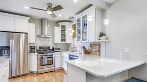 A modern kitchen with white cabinets, stainless steel appliances, and a marble island. - Steps to Short Beach: Ocean-View Apt w/ Deck! (Winthrop)