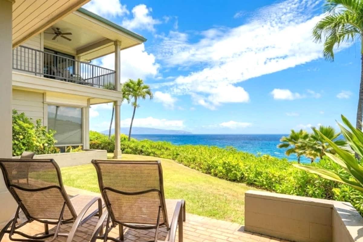 Uma casa de dois andares com uma varanda com vista para a paisagem oceânica.
