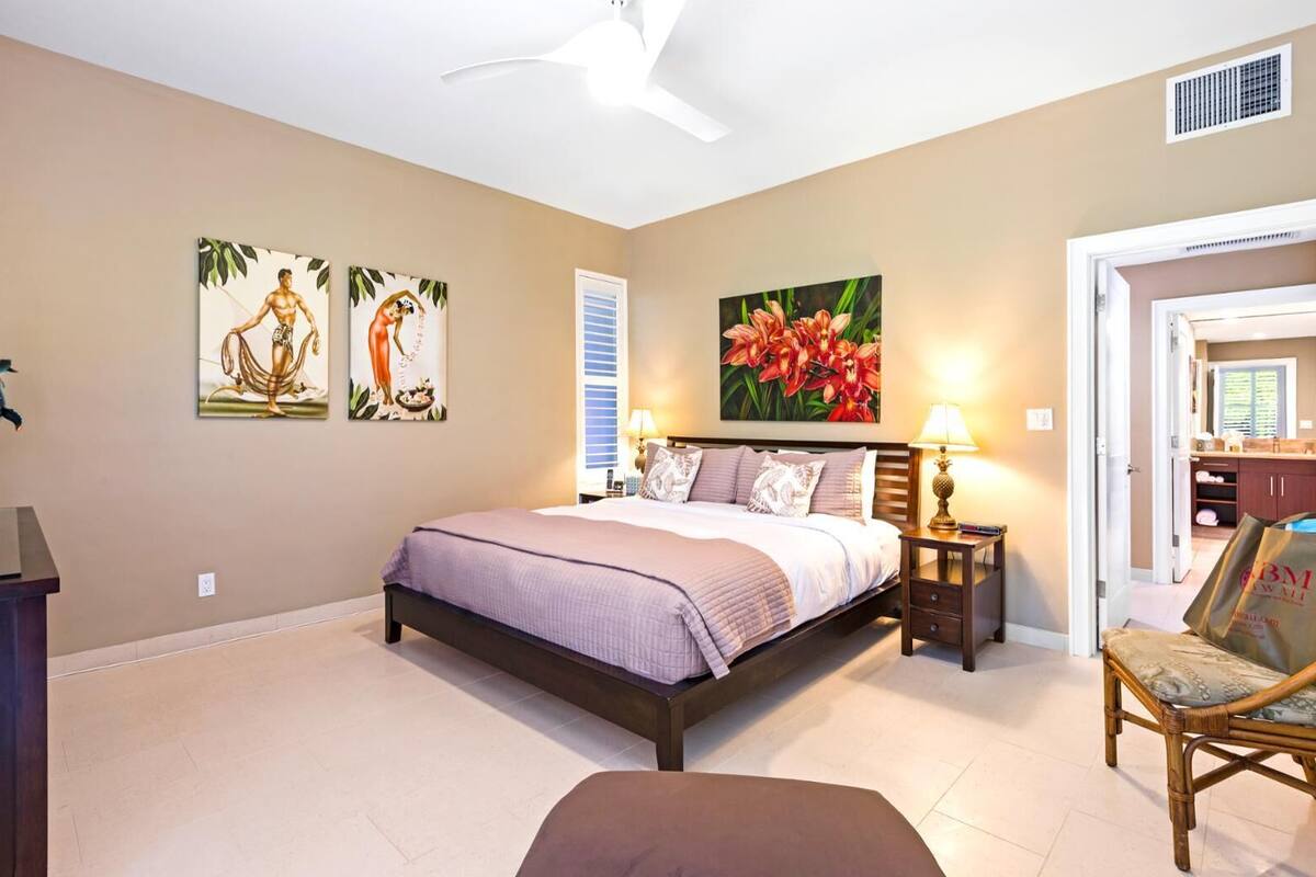 Quarto com cama, mesas de cabeceira, uma cadeira e obras de arte nas paredes.