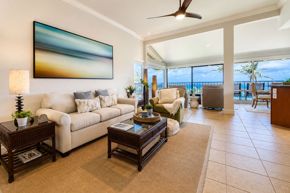 A spacious living room with a large window overlooking a scenic view, a ceiling fan, and a modern fireplace.